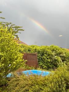 a rainbow over a garden with a swimming pool at Charmante chambre Chalet in Crozet