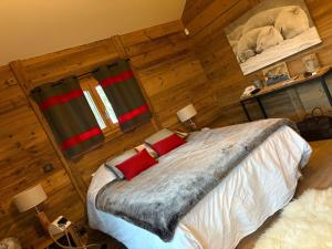 a bedroom with wooden walls and a bed with red pillows at Charmante chambre Chalet in Crozet