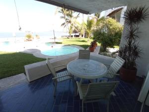 a patio with a table and chairs and a pool at Condominio Los Corales in Manzanillo