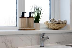 a bathroom sink with a window ledge with two bottles at Peaceful hideaway with homely comforts in Timperley +26 photos