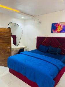 ein Schlafzimmer mit einem blauen Bett und einem Spiegel in der Unterkunft Double Homes in Agege