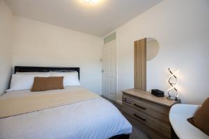 a bedroom with a bed and a dresser with a mirror at Peaceful hideaway with homely comforts in Timperley
