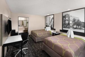 a hotel room with two beds and a desk at Super 8 by Wyndham Biloxi at the Beach in Biloxi