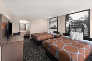 a hotel room with two beds and a flat screen tv at Super 8 by Wyndham Biloxi at the Beach in Biloxi +65 photos