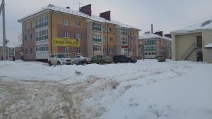 ジヴェエヴォにあるАпартаменты на Симанина 2の建物の前に車を駐車した雪屋根付き駐車場