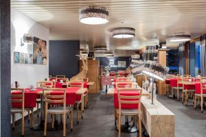 a restaurant with wooden tables and red chairs at Hotel du Lac in Crans-Montana