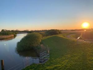 a view of a river with the sunset in the background at Landhaus Baumhöfer in Apen +3 photos