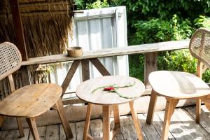 two chairs and a table with a flower on a deck at Bali Hidden Lemukih in Sawan