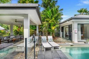 a villa with a swimming pool and a house at Belle Escapes Castaways in Palm Cove