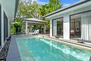 a swimming pool in front of a house at Belle Escapes Castaways in Palm Cove