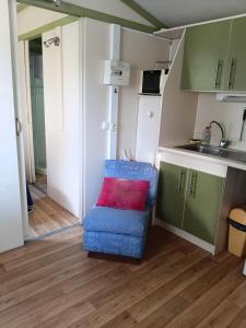 a small kitchen with a blue chair with a red pillow at Bungalow tonga in Moncetz-lʼAbbaye