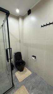 a bathroom with a black toilet in a stall at Yassi Apartment in Türkistan