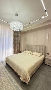 a bedroom with a large bed and a chandelier at Yassi Apartment in Türkistan