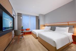 a hotel room with two beds and a flat screen tv at Novotel Living Hangzhou International Convention Center in Hangzhou