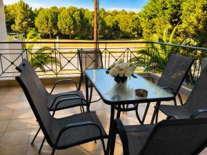 a table and chairs with a vase of flowers on a balcony at Angel Luxury Apartments in Keramoti