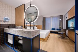 a hotel room with a bed and a sink and a mirror at Novotel Living Hangzhou International Convention Center in Hangzhou +20 photos