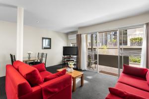 a living room with two red couches and a tv at Bay View Villas in Hobart