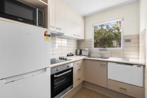 a white kitchen with a sink and a microwave at Bay View Villas in Hobart