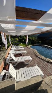 a row of white lounge chairs under an umbrella next to a pool at GSpace in Yaremche