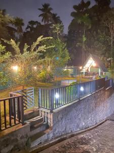 a stone wall with a gate and a house at night at Beloved Regency Homestay in Kandy