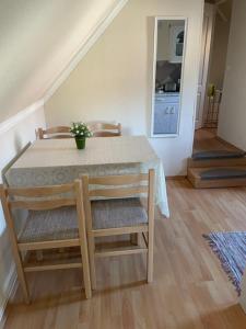 a dining room table with two chairs and a table with a plant at Kamilla Apartman in Fonyód
