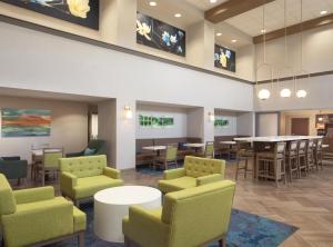 a waiting room with green chairs and a table and tables at Hampton Inn & Suites Natchez in Natchez
