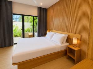 a bedroom with a white bed and a large window at Isola Alifu in Feridhoo