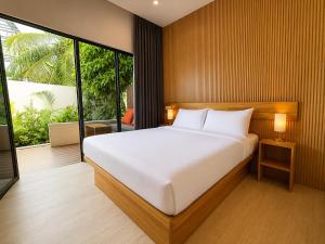 a bedroom with a white bed and a large window at Isola Alifu in Feridhoo