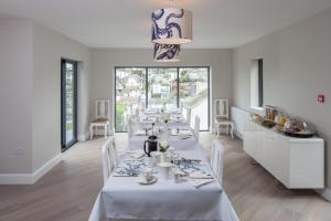 a dining room with a white table with white chairs at Driftwood B&B in Brixham