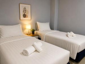 two beds in a room with white sheets and towels at Chaba CBP Chiang Mai in Chiang Mai