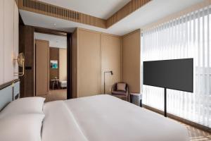 a bedroom with a bed and a flat screen tv at Grand Hyatt Kunming in Kunming