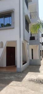 a white building with a door and a palm tree at Diddy & Eddy's apartment in Malindi +4 photos