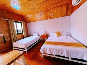 a bedroom with two beds and a wooden ceiling at Retreat Bungalow in Phong Nha