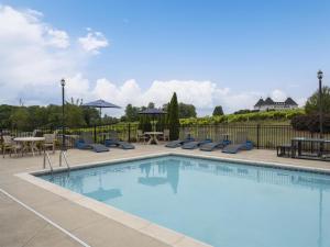 a swimming pool with chairs and tables and a fence at Hampton Inn & Suites Braselton in Braselton