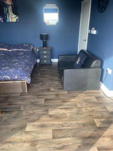 a bedroom with a bed and a couch and blue walls at Springwood cabin in Kirkhamgate