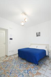 a bedroom with a blue bed and a white wall at B&B Centro Storico in Diamante