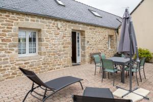 a patio with a table and chairs and an umbrella at Gîte Ty Traon piscine partagée in Ergué-Gabéric