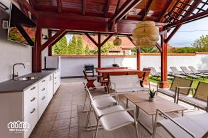 an outdoor kitchen and dining area with a table and chairs at BORG VendégHázak - Tiszakécske in Tiszakécske