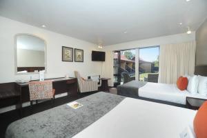 a hotel room with two beds and a desk at Quality Hotel Lincoln Green in Auckland
