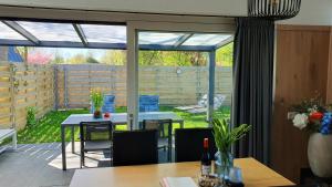 a conservatory with a patio with a table and chairs at Luxe vakantiebungalow Rust, Ruimte en Privacy in Dirkshorn