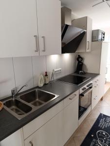 a kitchen with white cabinets and a stainless steel sink at Monteurwohnung,Ferienwohnung in Lüdenscheid
