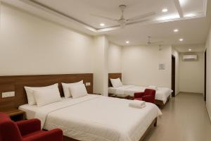 a hotel room with two beds and red chairs at Hotel The Amrit in Jabalpur +48 photos