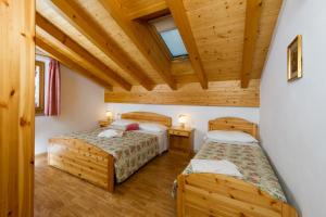 dwa łóżka w pokoju z drewnianym sufitem w obiekcie Residence Villa Boschetto w mieście Carano