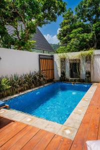 a swimming pool in a backyard with a wooden deck at THE SANDS LOMBOK in Mangsit