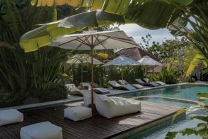 a pool with chairs and umbrellas next to a swimming pool at YŪN Uluwatu in Uluwatu