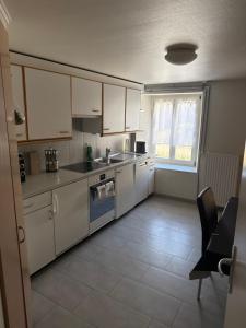 a small kitchen with white cabinets and a window at Pâquier 3 in Saint-Sulpice
