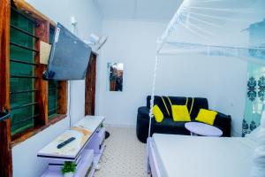 a room with two beds and a tv and a couch at Avana Studio Watamu in Watamu