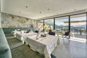 a restaurant with tables and chairs and large windows at Hotel Avelina in Avelengo