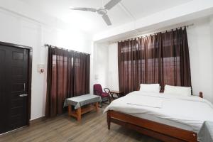 a bedroom with a bed and a chair and a window at Hotel Zimin Ziro in Ziro
