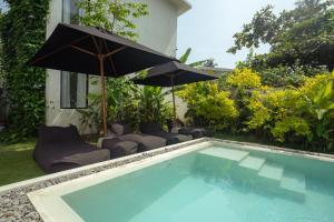 a swimming pool with an umbrella and some chairs at Air Villa in Ahangama